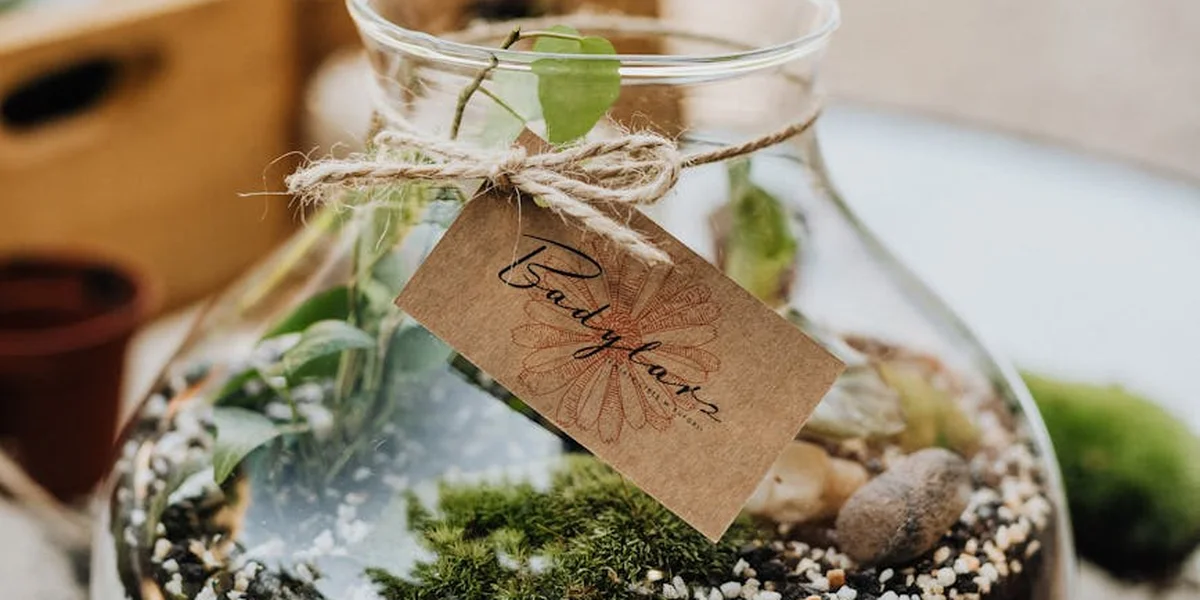Glass jar with a green plant sprig, twine around the neck, and a hanging brown tag