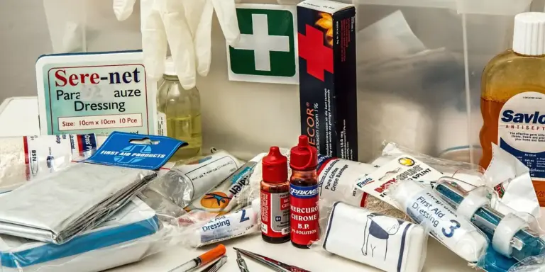 Assorted first aid supplies on a countertop, including bandages, bottles, and a green cross sign.
